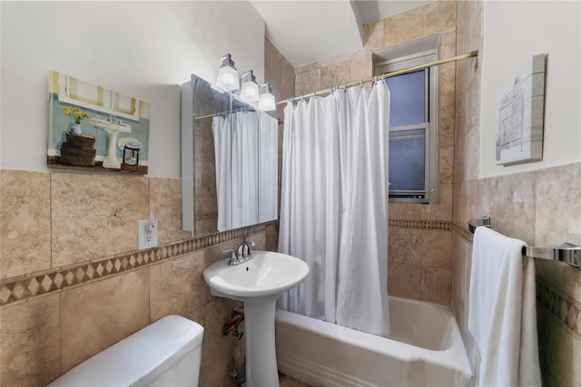 bathroom featuring toilet, shower / bath combo with shower curtain, and tile walls