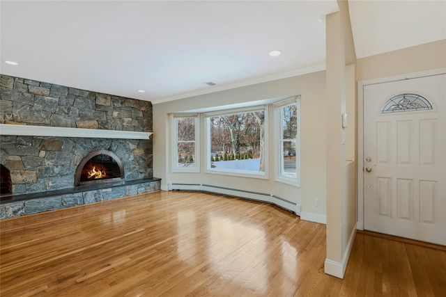 unfurnished living room featuring hardwood / wood-style floors, ornamental molding, a fireplace, and a baseboard heating unit