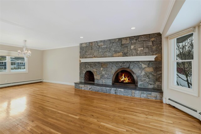 unfurnished living room with a baseboard radiator, a stone fireplace, a notable chandelier, light hardwood / wood-style floors, and ornamental molding