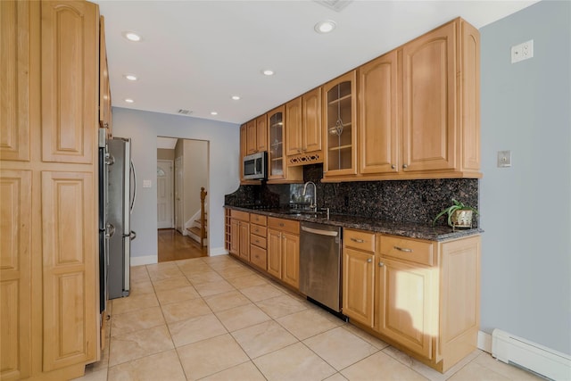 kitchen with dark stone countertops, light tile patterned floors, stainless steel appliances, and a baseboard heating unit