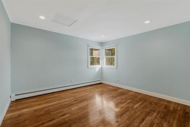 empty room featuring hardwood / wood-style floors and a baseboard heating unit