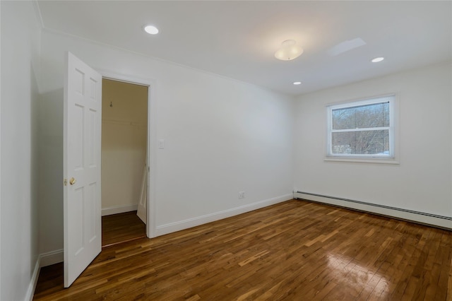 empty room with dark wood-type flooring and a baseboard heating unit