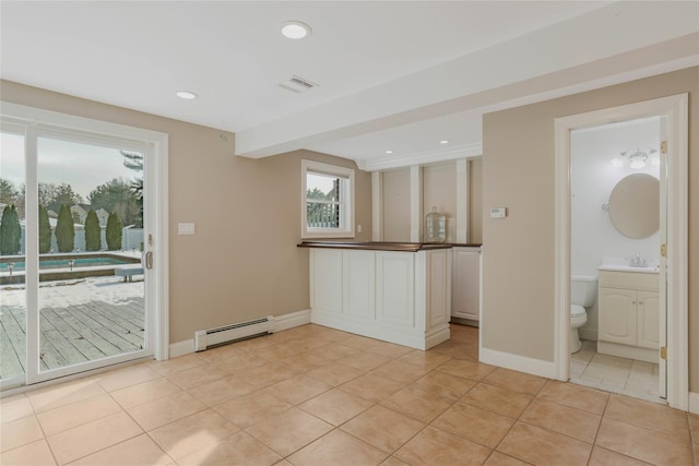 empty room with light tile patterned flooring, sink, and baseboard heating