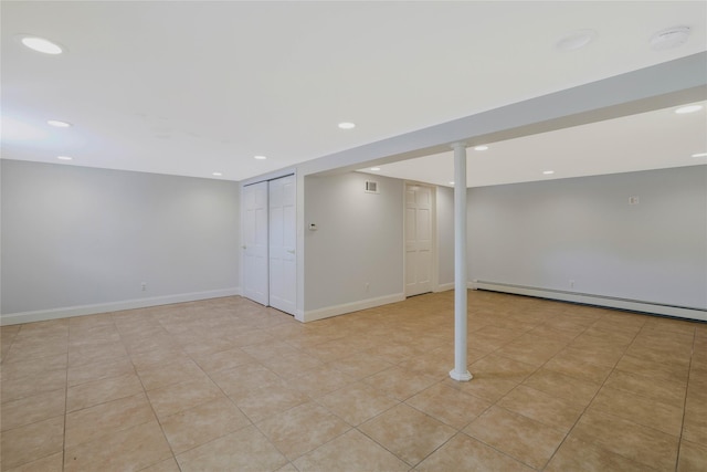 basement featuring light tile patterned floors and a baseboard heating unit