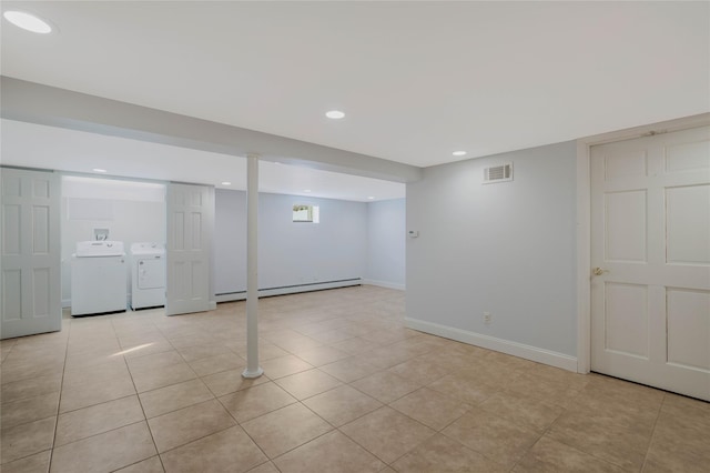 basement with independent washer and dryer, a baseboard heating unit, and light tile patterned flooring