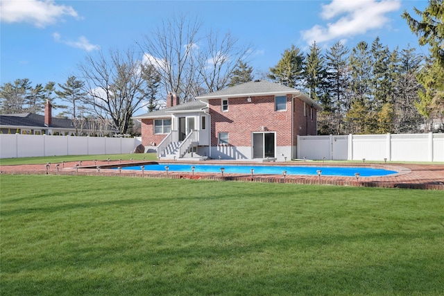 rear view of property featuring a fenced in pool and a lawn