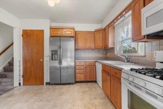 kitchen featuring sink, tasteful backsplash, and white appliances