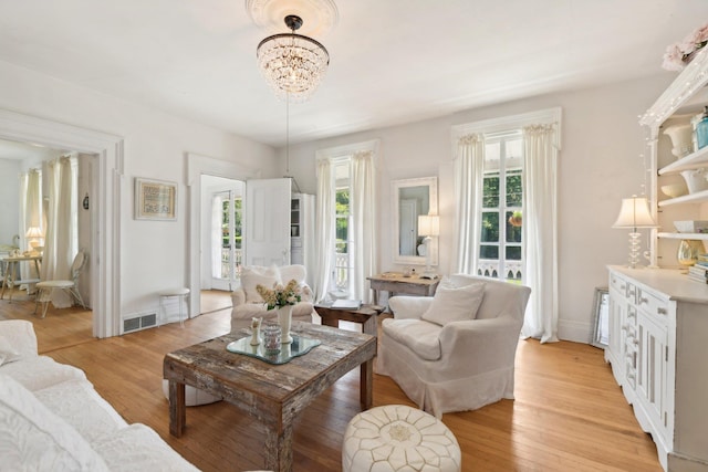 living room with light hardwood / wood-style floors and a notable chandelier