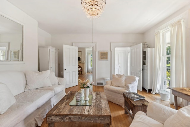 living room with a healthy amount of sunlight, a notable chandelier, and light wood-type flooring