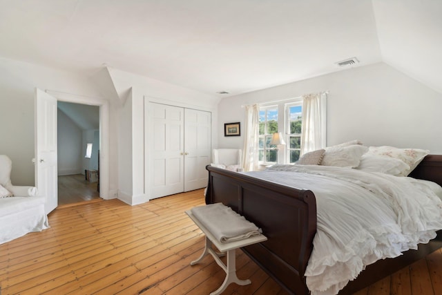 bedroom with a closet, lofted ceiling, and light wood-type flooring