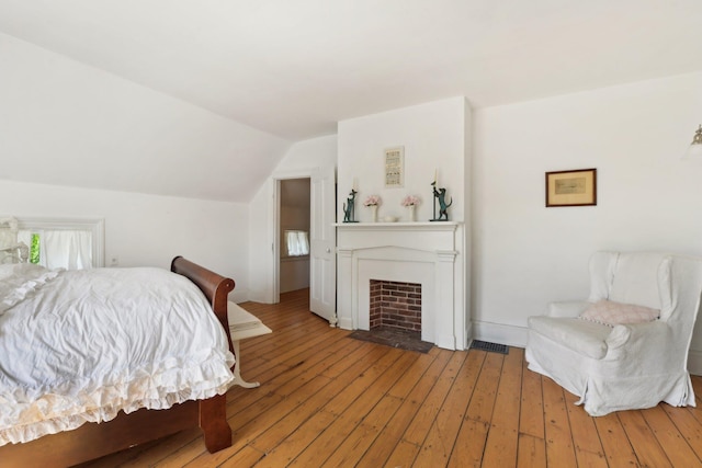 45 Shore Rd, East Setauket, NY 11733 - bedroom featuring light wood-type flooring, vaulted ceiling, and a fireplace with flush hearth