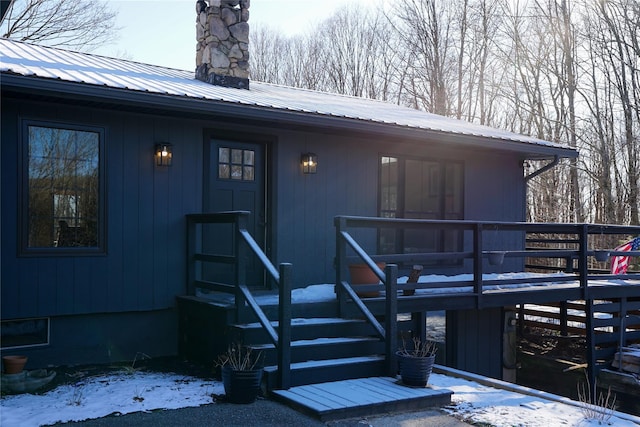 snow covered property entrance featuring a wooden deck