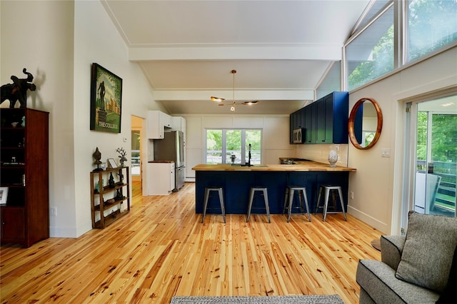 kitchen featuring white cabinetry, stainless steel appliances, a kitchen breakfast bar, kitchen peninsula, and light hardwood / wood-style floors