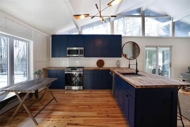 kitchen featuring blue cabinets, wooden counters, and appliances with stainless steel finishes