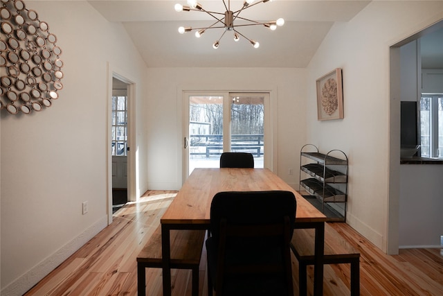 dining space featuring a chandelier, light hardwood / wood-style floors, and vaulted ceiling