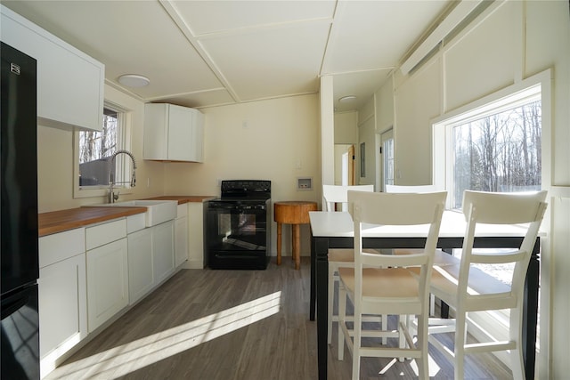 kitchen featuring butcher block counters, white cabinetry, sink, and black appliances