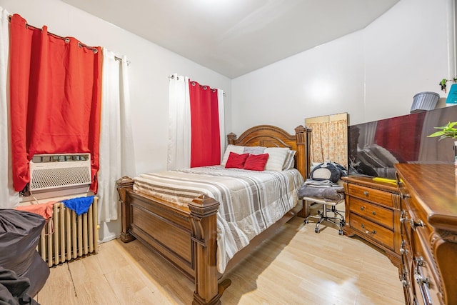 bedroom with radiator heating unit, light wood-type flooring, and cooling unit