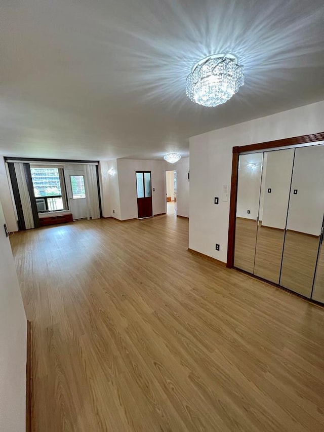 unfurnished living room featuring light hardwood / wood-style flooring and a chandelier