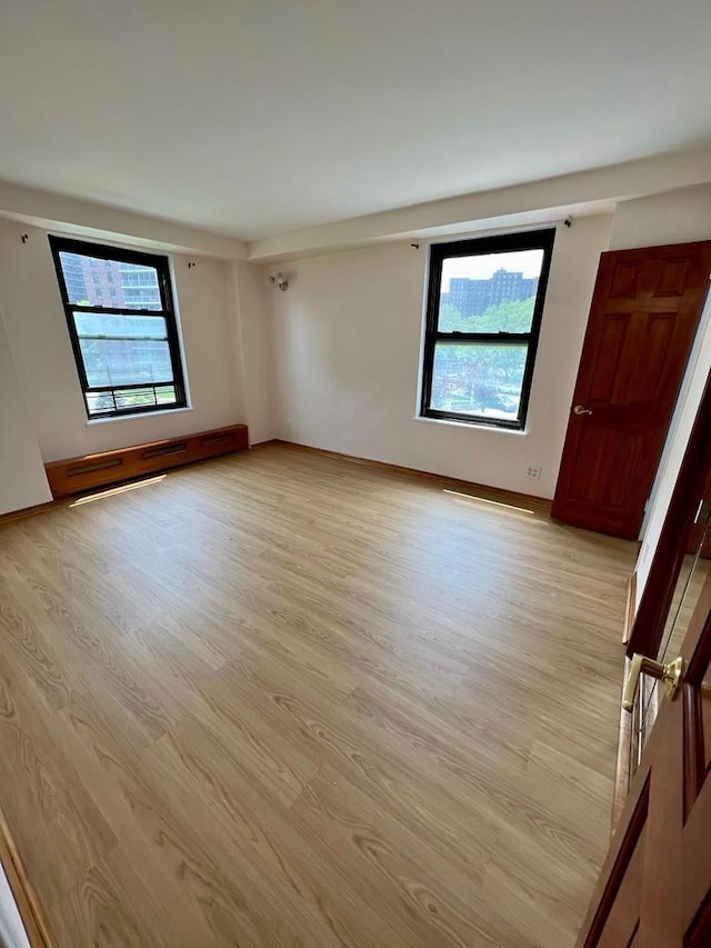 empty room featuring a baseboard radiator and light wood-type flooring