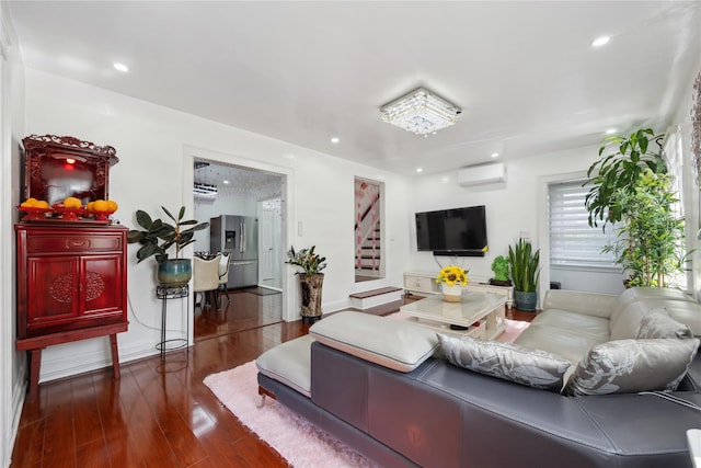 living room with a wall mounted AC, dark wood-type flooring, and a notable chandelier