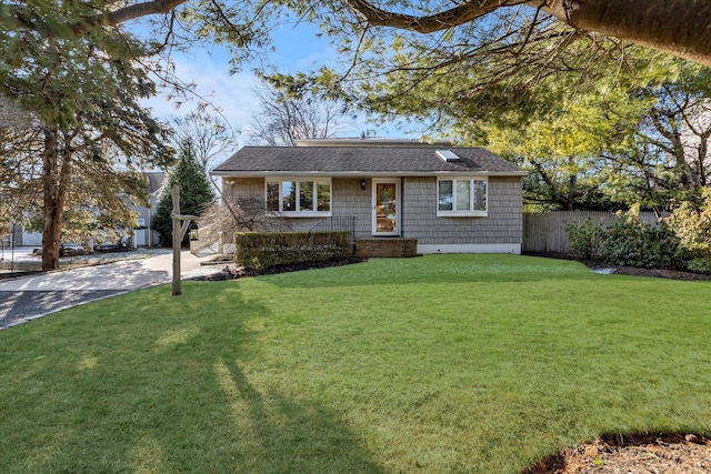 view of front of house with a front lawn, a shingled roof, driveway, and fence