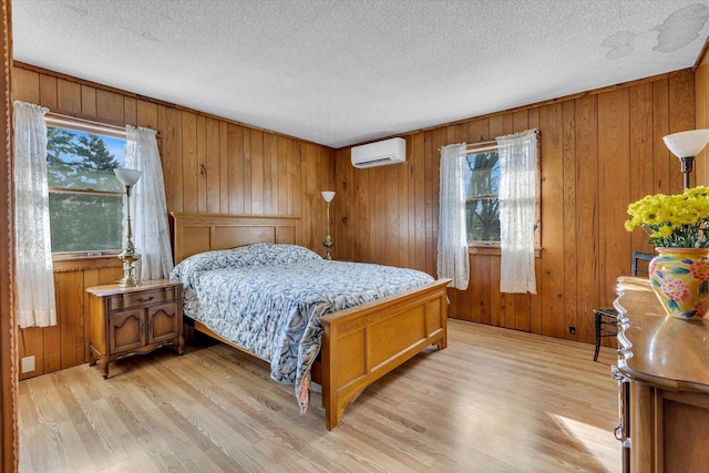 bedroom featuring wood walls, light hardwood / wood-style flooring, multiple windows, and a wall mounted AC