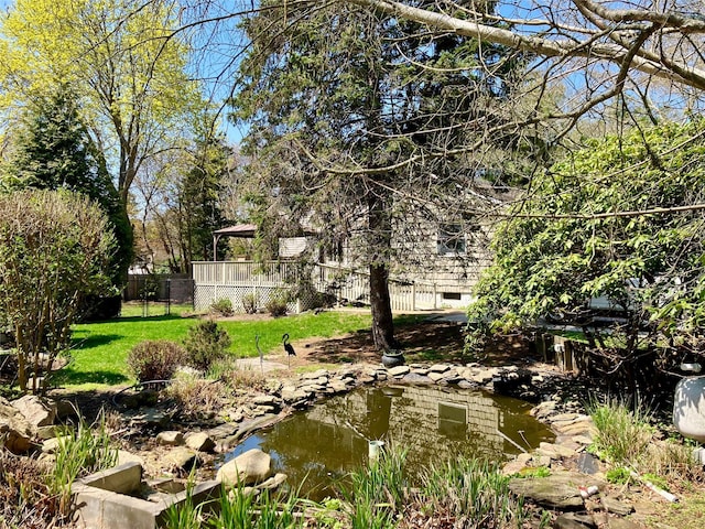 view of yard featuring fence and a garden pond