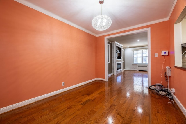 unfurnished living room with a fireplace, wood-type flooring, ornamental molding, and a notable chandelier