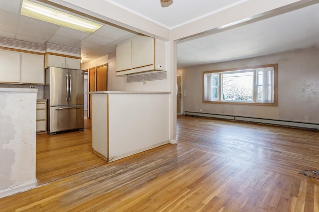 kitchen featuring white cabinetry, stainless steel refrigerator, a baseboard heating unit, and light hardwood / wood-style flooring