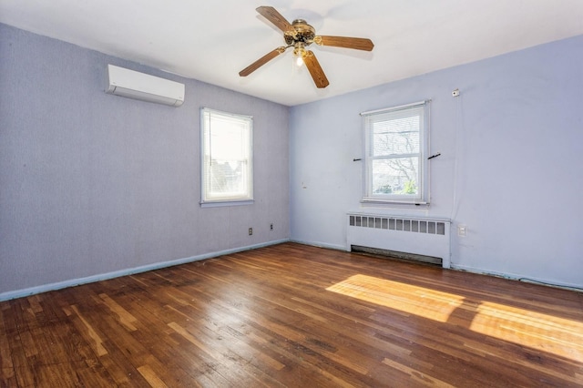 spare room featuring a wall mounted AC, radiator, dark wood-type flooring, and ceiling fan