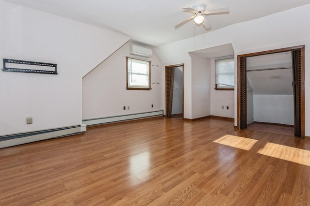 bonus room featuring a wall mounted air conditioner, ceiling fan, a baseboard heating unit, light hardwood / wood-style floors, and lofted ceiling