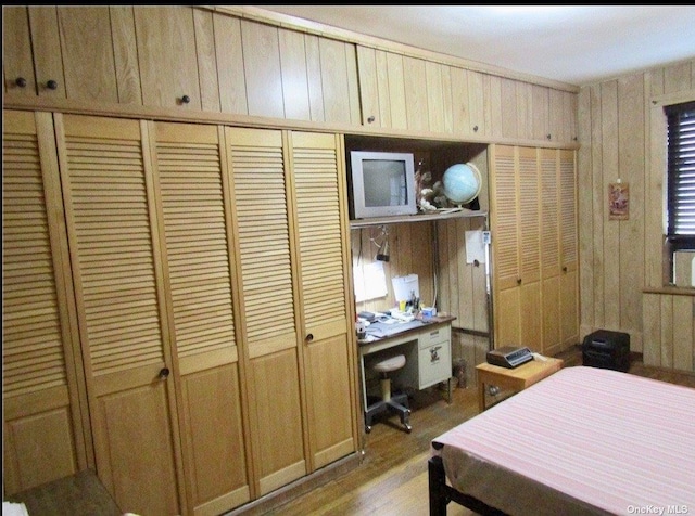 bedroom with light hardwood / wood-style floors, a closet, and wood walls