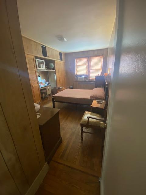 bedroom with dark hardwood / wood-style floors and wooden walls