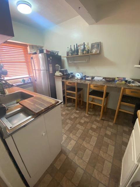 kitchen with white cabinets, sink, and stainless steel refrigerator