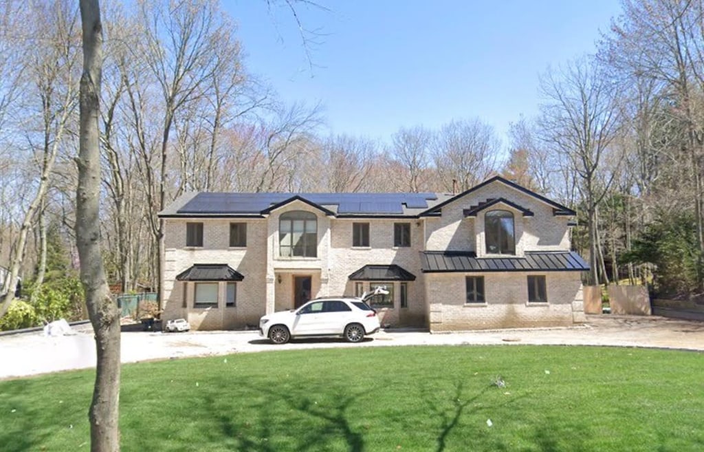 view of front of property with solar panels and a front yard