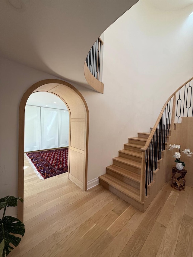 stairway with arched walkways and wood finished floors