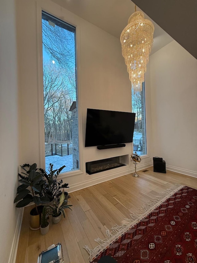 living area with baseboards, wood finished floors, and a notable chandelier