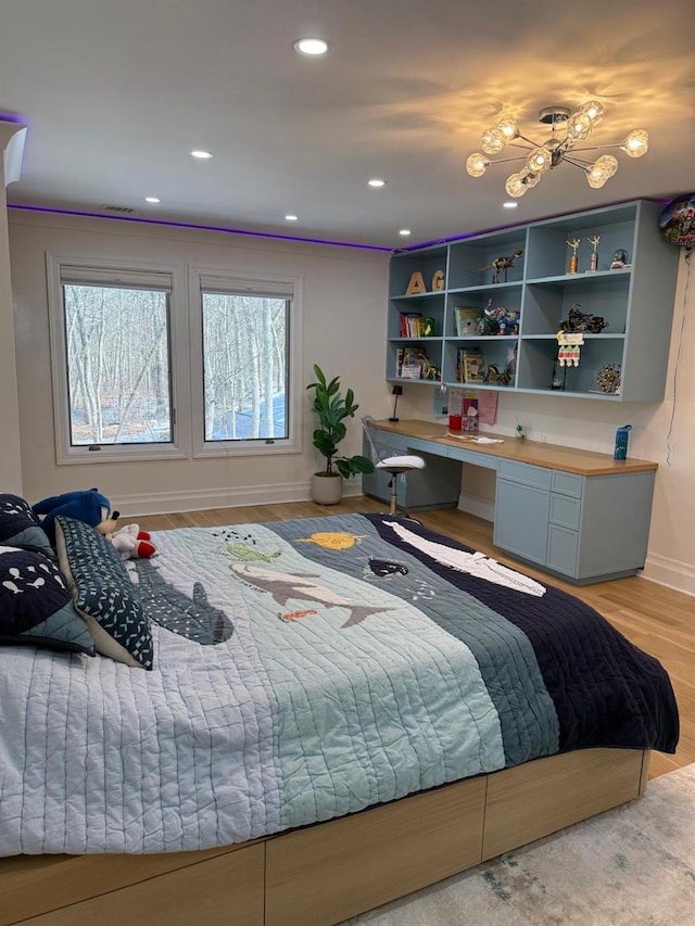 bedroom with light wood finished floors, visible vents, baseboards, built in desk, and recessed lighting