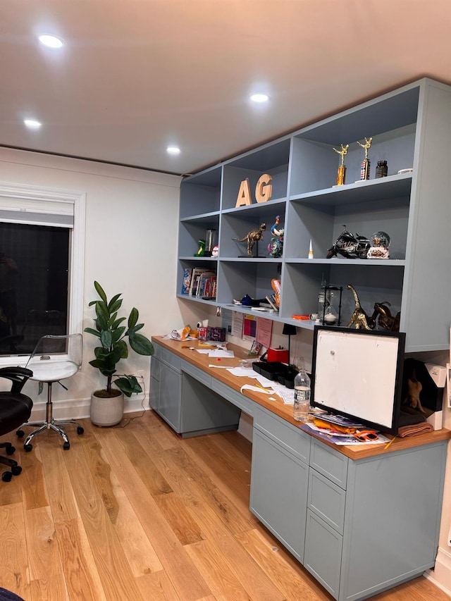 home office with light wood finished floors, built in study area, and recessed lighting