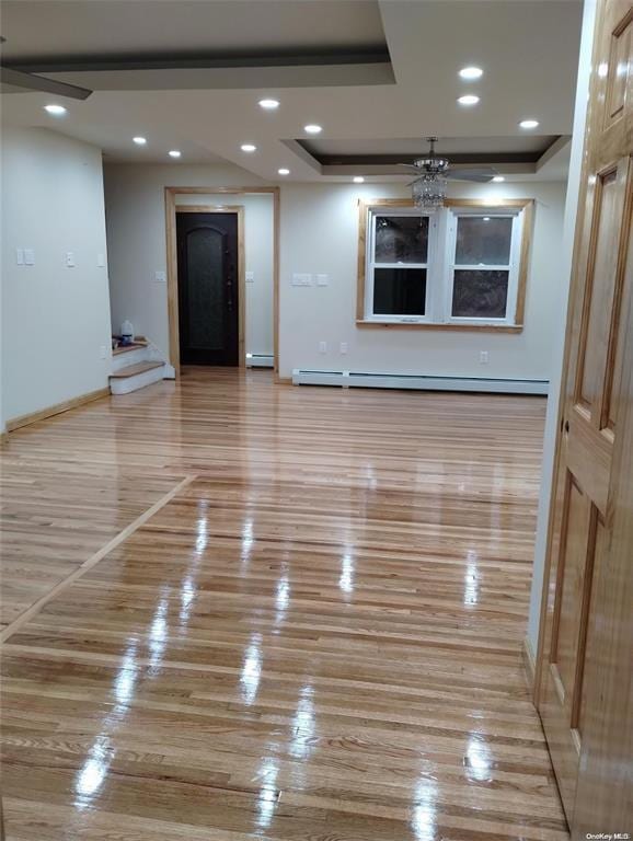 unfurnished room with a raised ceiling, ceiling fan, and baseboard heating