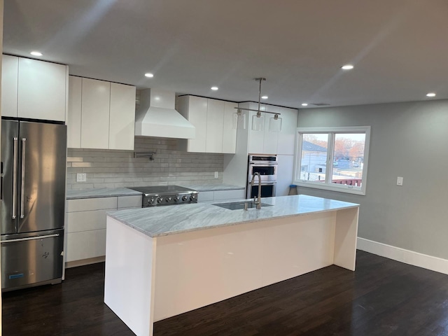 kitchen with high end appliances, custom exhaust hood, white cabinets, and a center island with sink