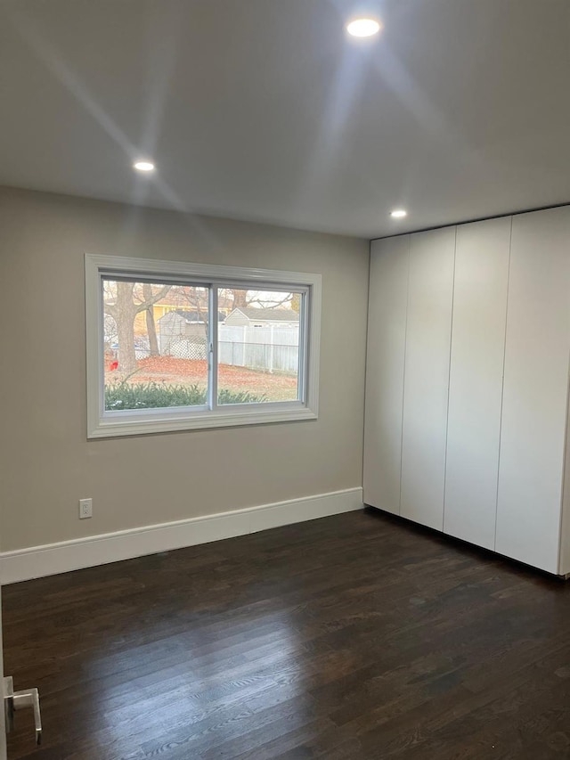 unfurnished bedroom with dark hardwood / wood-style floors and a closet