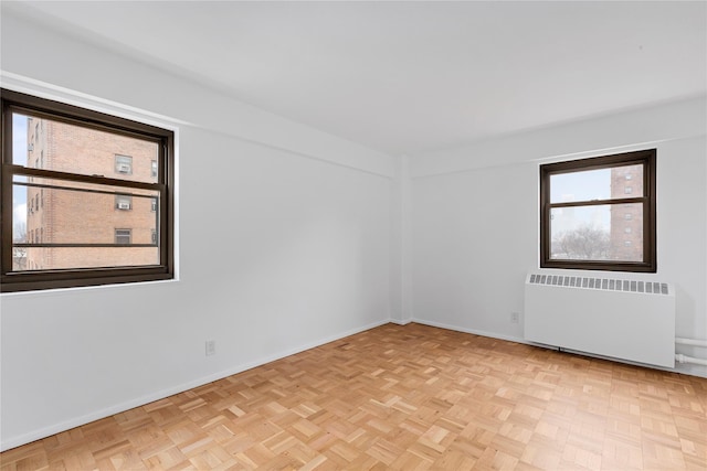 unfurnished room featuring radiator and light parquet floors