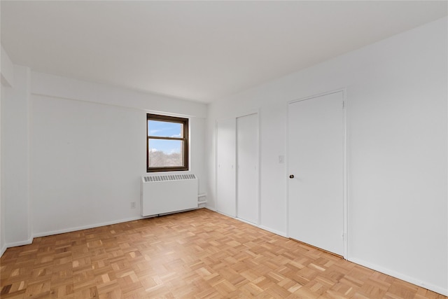 unfurnished bedroom featuring radiator heating unit and light parquet flooring