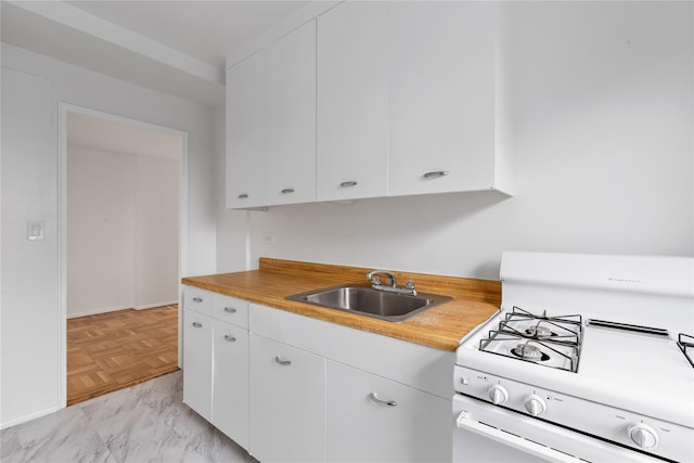 kitchen with white cabinets, light parquet flooring, gas range gas stove, and sink