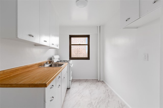 kitchen featuring white range oven, white cabinetry, and sink