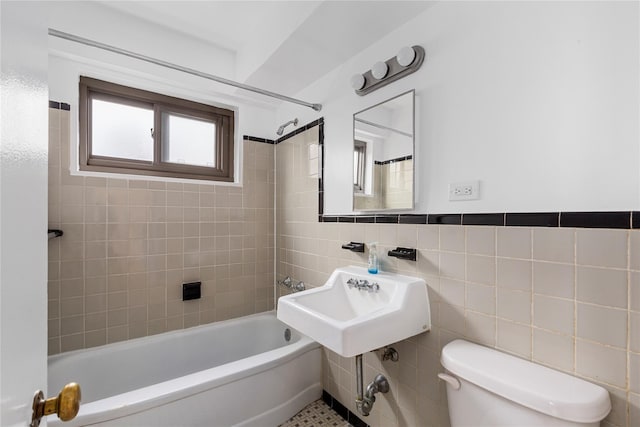 bathroom with toilet, tile walls, and tiled shower / bath