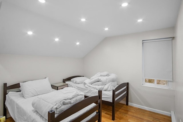 bedroom with light hardwood / wood-style flooring, a baseboard radiator, and vaulted ceiling