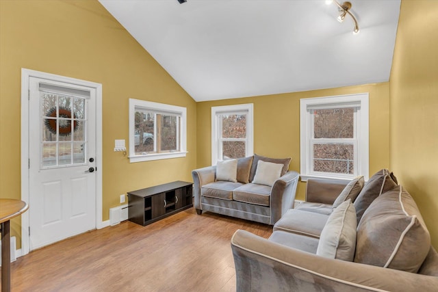 living room with vaulted ceiling, rail lighting, light wood-type flooring, and a healthy amount of sunlight