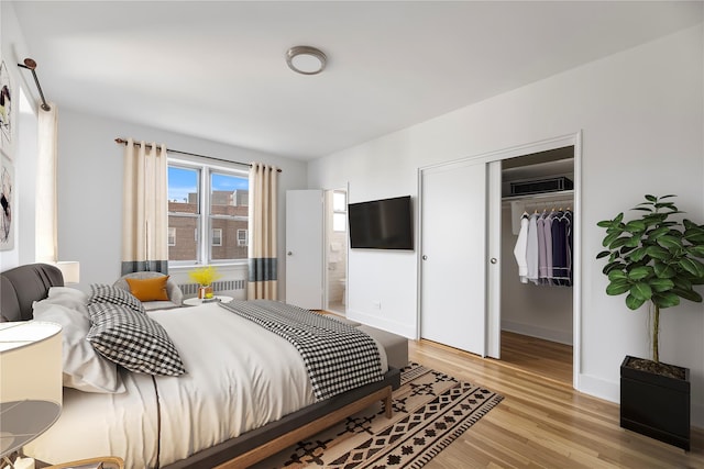 bedroom with radiator, light wood-type flooring, and a closet